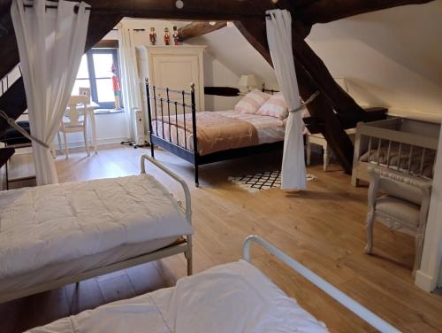 a attic bedroom with two beds and a table and chairs at Le petit Moulin de Drée in Drée