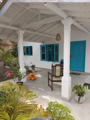 a porch with blue doors and a bench and plants at Amma's Garden in Unawatuna