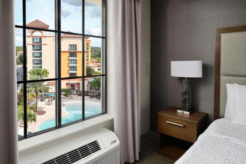 a bedroom with a bed and a window with a view of a pool at Homewood Suites By Hilton Orlando Flamingo Crossings, Fl in Orlando