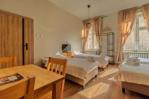 a room with three beds and a table and a table and chairs at Hostel H360 - dawniej Hotelik Relax in Łódź