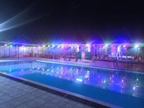 a swimming pool at night with lights on at Royal Resort in Indore