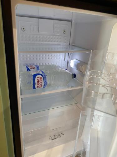 an open refrigerator with a bottle of milk and a bag of milk at Cil y Coed Luxury Pod in Machynlleth