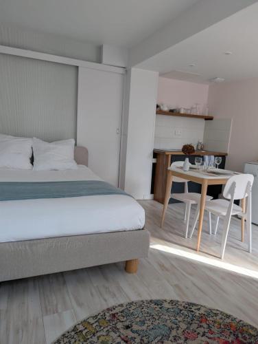 a bedroom with a bed and a table and chairs at La loge Diane, à deux pas du château et son jardin à la française in Chantilly
