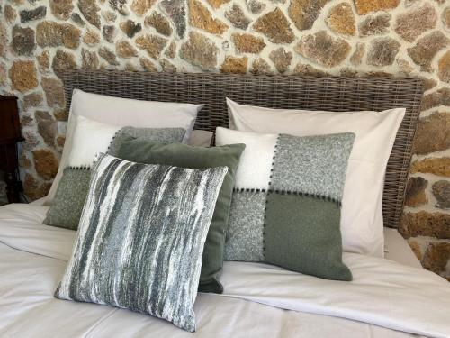 un letto con diversi cuscini sopra e un muro di pietra di Aux 3 Forêts a Bizeneuille