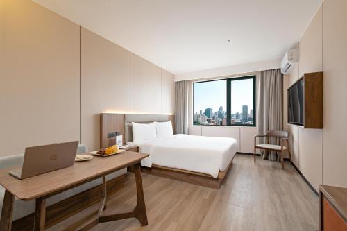 a hotel room with a bed and a desk with a laptop at Model J Hotel Jakarta Central Park 曼居酒店 雅加达中央公园店 in Jakarta