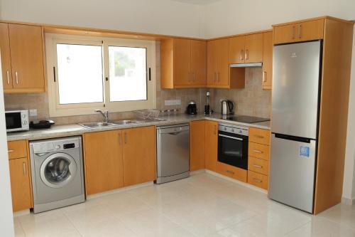 a kitchen with wooden cabinets and a stainless steel refrigerator at Anthorina Villa 10 in Protaras