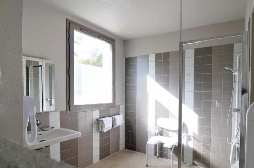 un bagno con lavandino e doccia con finestra di Relais Fasthotel Port Lauragais ad Avignonet-de-Lauragais