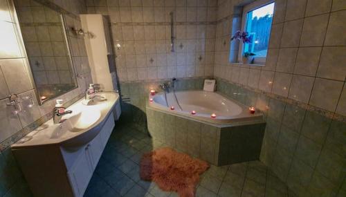 a bathroom with a tub and a sink and a mirror at Goričko Homes in Mačkovci