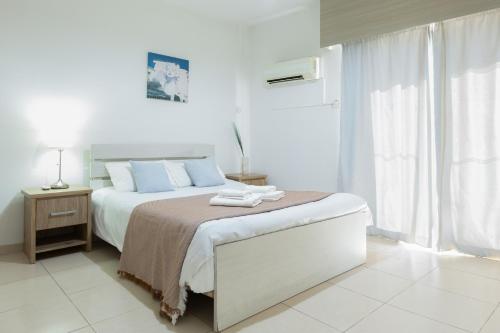 a white bedroom with a bed with two towels on it at Tiffany City Apartments in Larnaca