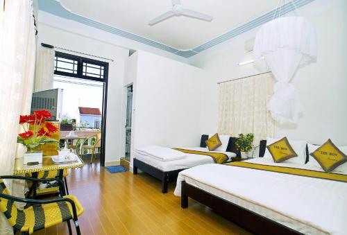 a bedroom with two beds and a table and a window at Thu Bon Riverside Homestay in Hoi An