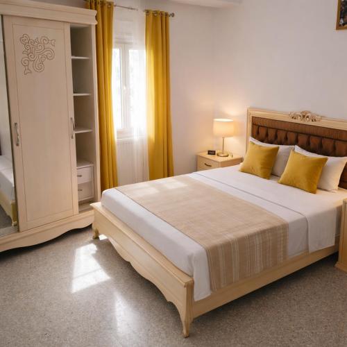 a bedroom with a large bed with yellow curtains at La Perle de Hergla Maison d Hotes in Harqalah