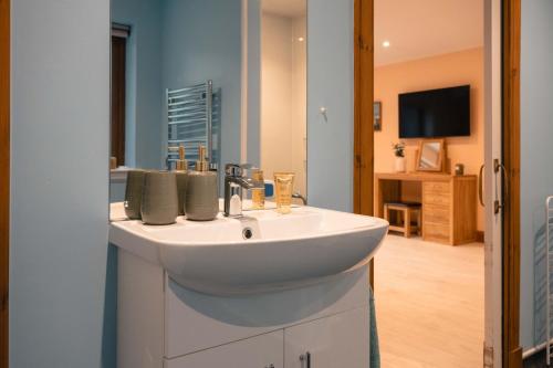 a bathroom with a white sink and a television at Lakeside Lodge, Views, Hot Tub & Fully Accessible in Elgin