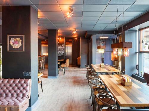 a restaurant with tables and chairs and a couch at ibis Birmingham Airport Terminal Building - NEC in Bickenhill