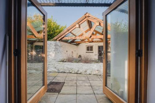 an open glass door of a house with a stone wall at Cosy Welsh Cottage in St Davids Centre with Garden in St. Davids
