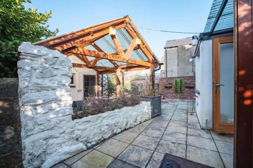a barn conversion with a wooden pergola and a stone wall at Cosy Welsh Cottage in St Davids Centre with Garden in St. Davids
