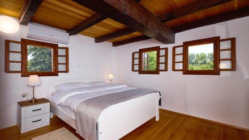 a bedroom with a white bed and windows at Villa 77 by Villas Guide in Sisak