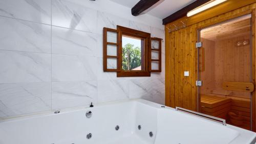 a large white tub in a bathroom with a window at Villa 77 by Villas Guide in Sisak