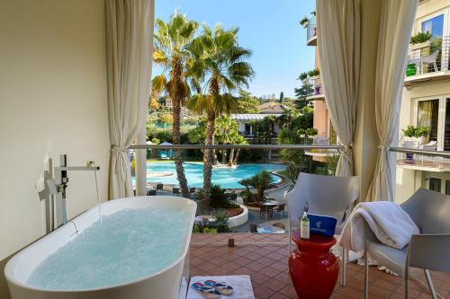 a bath tub in a balcony with a view of a pool at Color Hotel Style, Design & Gourmet in Bardolino