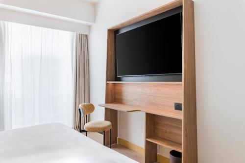 a room with a bed and a flat screen tv at Hampton by Hilton Bordeaux Merignac Airport in Mérignac