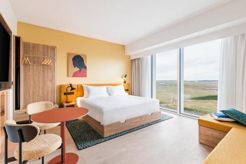 a hotel room with a bed and a table at Hampton by Hilton Bordeaux Merignac Airport in Mérignac