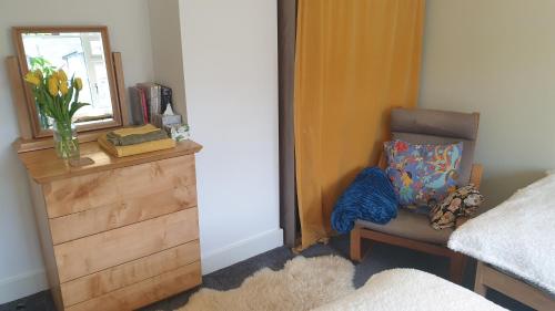 a bedroom with a dresser and a chair and a mirror at 15 Kershaw Crescent in Luddenden Foot