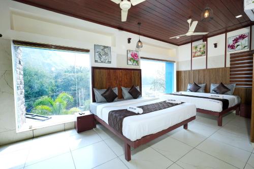a bedroom with two beds and a large window at Velan Temple View in Palni