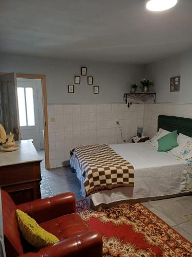 a bedroom with a large bed and a chair at Alojamento Excalibur in Meda
