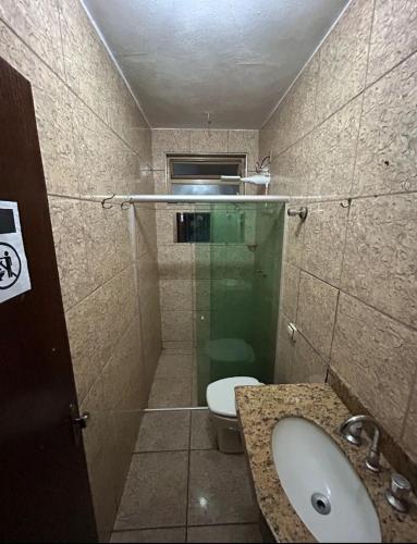 a small bathroom with a toilet and a sink at Quarto individual Aconchego in Divinópolis