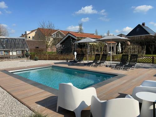 a swimming pool with chairs and umbrellas in a yard at Hoeve Altena Cottage in Woudrichem