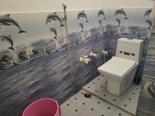 a bathroom with a toilet and dolphins on the wall at Narayan homestay guesthouse in Ayodhya