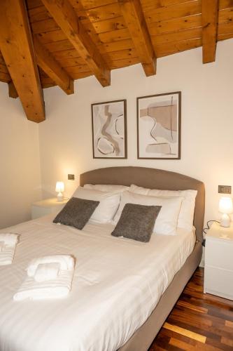 a bedroom with a large white bed with wooden ceilings at Liberty Apartment in Lovere