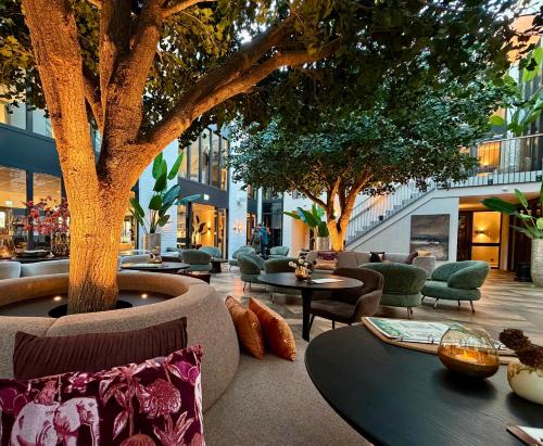 a patio with tables and chairs and trees at Eilandhotel Texel - Nieuw geopend hotel in De Cocksdorp