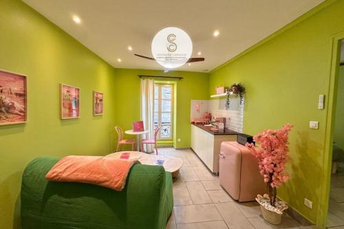 a living room with green walls and a kitchen at Arles Getaway - Le Flamant Vert in Arles