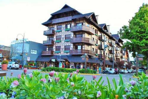 a building on a street with flowers in front of it at Apartamento Alto da Serra - 024 in Gramado