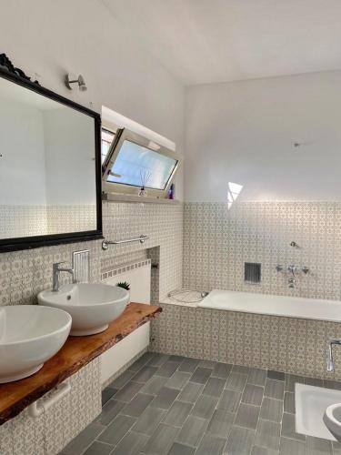 a bathroom with two sinks and a tub and a mirror at Dori Affittacamere in San Lorenzo