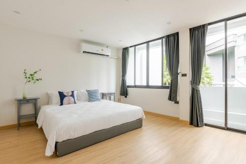 a white bedroom with a bed and large windows at The Mellow at Sathorn in Chinatown