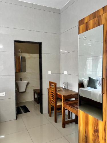 a bedroom with a table and a bed and a bathroom at Nest Inn in Suntikoppa