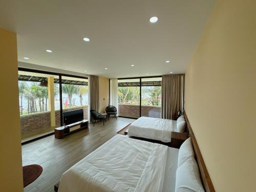 a hotel room with two beds and a large window at Con Nho RiverHouse Hue in Thôn Tiên Nộn