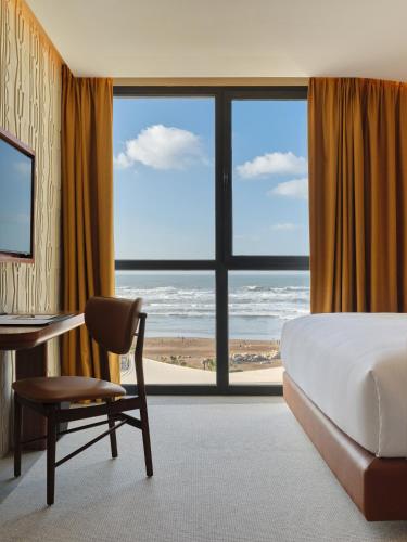 a bedroom with a bed and a desk and a large window at Villa Sahrai, a Member of Design Hotels in Casablanca