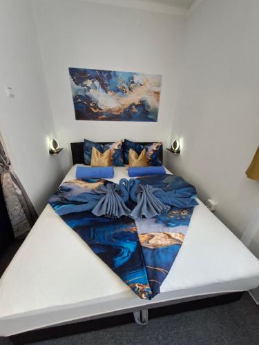a bedroom with a white bed with a painting on the wall at Mia Apartman Salgótarján in Salgótarján