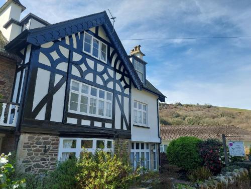 a black and white house with a hill in the background at The Denes Guest House in Lynton