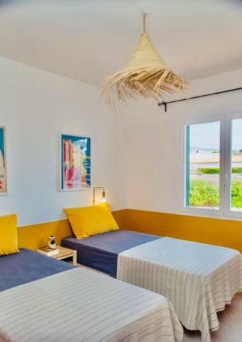 a bedroom with two beds and a window at Villa Gabriela - piscine privée proche Punta Prima in Punta Prima