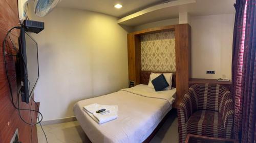 a small bedroom with a bed and a chair at Hotel Adya Classsic in Kammasandra