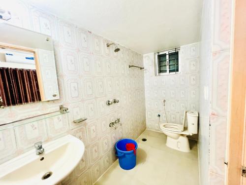a white bathroom with a sink and a toilet at Tourist Home in Ābdullāpur