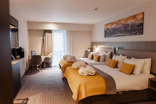 a hotel room with two beds and a television at Maldron Hotel Newcastle in Newcastle upon Tyne