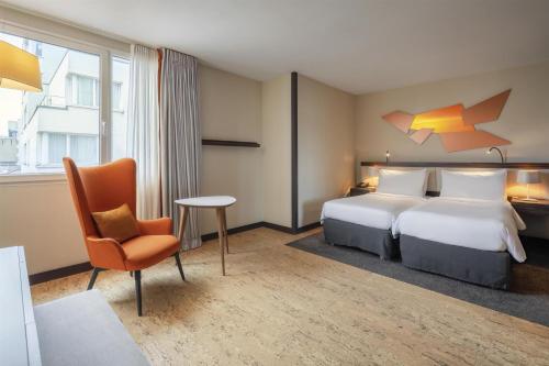 a hotel room with two beds and a chair at DoubleTree by Hilton Paris Boulogne in Boulogne-Billancourt