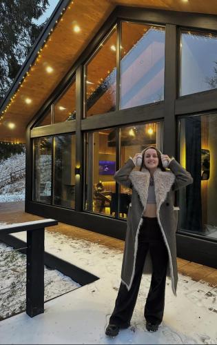 a woman standing in the snow in front of a building at Шале Ротило in Krivopolʼye