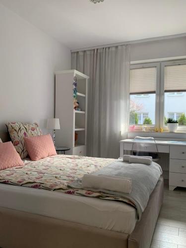 a bedroom with a bed with a desk and a window at LUX Apartament in Suwałki