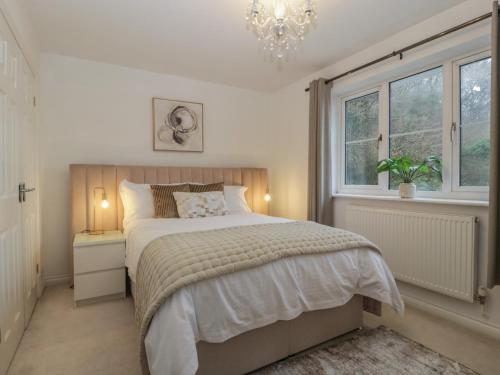 a bedroom with a bed and a chandelier and a window at 42 Ynys Y Nos in Neath