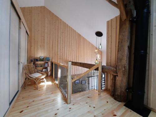a room with a wooden staircase with a chair at Grain d'orge et cornouiller in Bulson